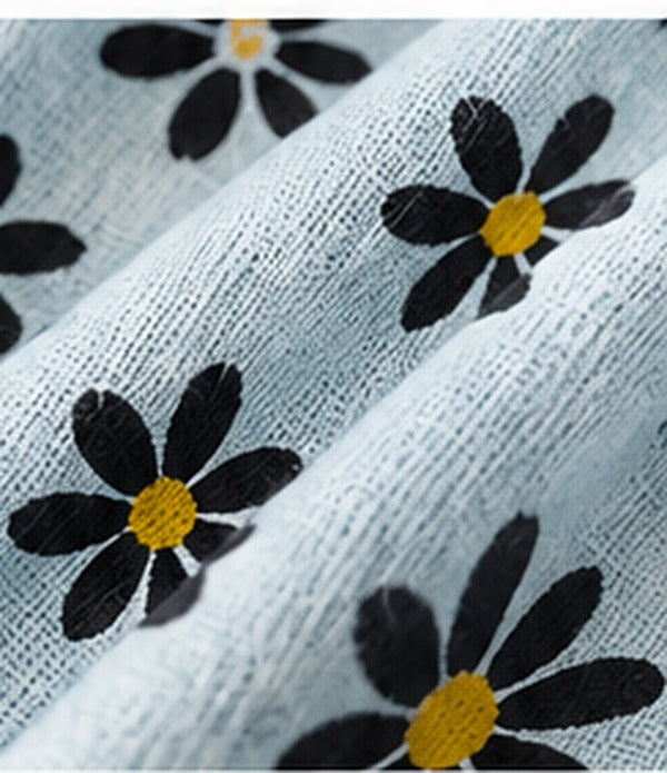 Fabric close-up of light-blue cotton-flax fabric with black daisy flowers and yellow centres